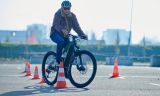 Eine Person, die mit einem Fahrrad auf einer StraÃe mit orangefarbenen Kegeln fÃ¤hrt