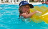 Ein Kind schwimmt in einem Pool mit einer Luftmatratze.