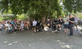 Eine Gruppe von Menschen, die auf BÃ¤nken saÃen, und eine Person, die Instrumente spielte