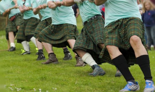 Eine Gruppe MÃ¤nner in Kilts, die an einem Seil ziehen