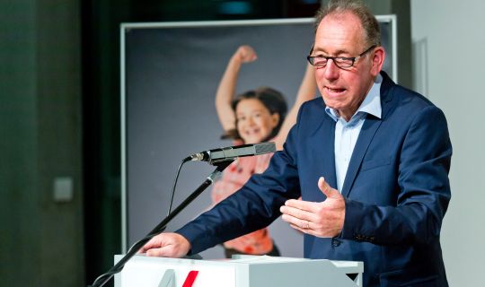 Eine Person, die mit einem Mikrofon an einem Podium steht Eine Person, die mit einem Mikrofon an einem Podium steht