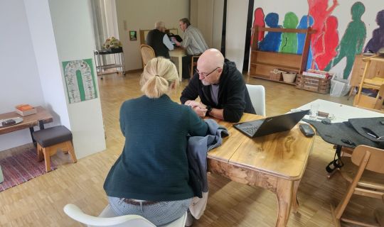 Eine Person und eine Person, die an einem Tisch mit einem Laptop sitzt Eine Person und eine Person, die an einem Tisch mit einem Laptop sitzt