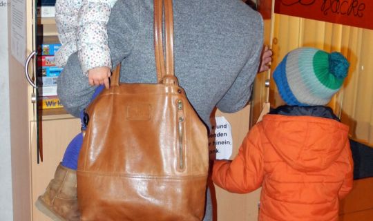 Eine Familie steht vor einem Schrank voller Brettspiele. Eine Familie steht vor einem Schrank voller Brettspiele.