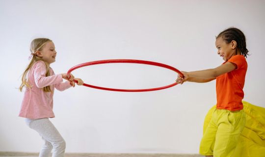 Eine Gruppe von Kindern, die mit einem Hula-Hoop-Reifen spielen.