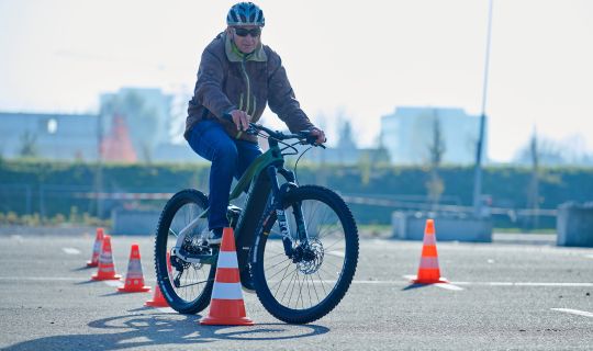 Eine Person, die mit einem Fahrrad auf einer StraÃe mit orangefarbenen Kegeln fährt Eine Person, die mit einem Fahrrad auf einer StraÃe mit orangefarbenen Kegeln fährt