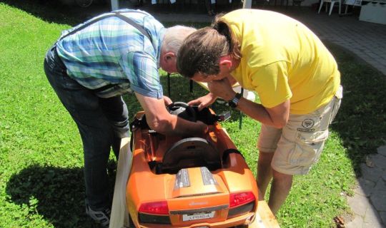 zwei Männer reparieren ein Spielzeugauto zwei Männer reparieren ein Spielzeugauto