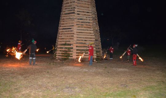 Eine Gruppe von Menschen, die Fackeln halten und vor einer Holzkonstruktion stehen Eine Gruppe von Menschen, die Fackeln halten und vor einer Holzkonstruktion stehen