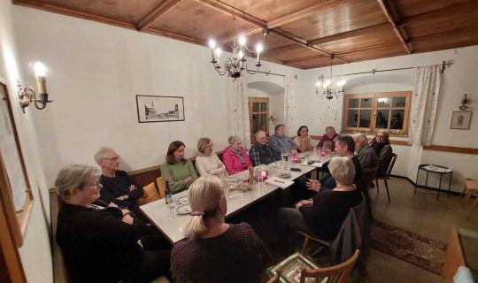 Eine Gruppe von Menschen, die um einen Tisch sitzen Eine Gruppe von Menschen, die um einen Tisch sitzen