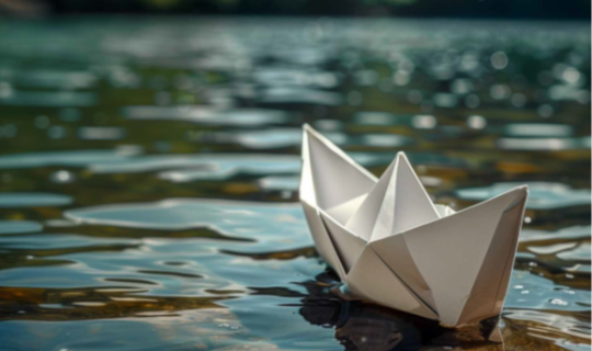 ein Papierboot, das auf dem Wasser treibt ein Papierboot, das auf dem Wasser treibt