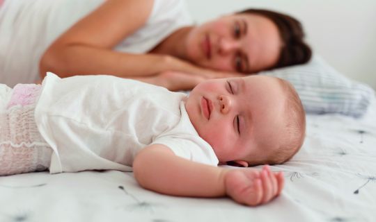 Eine Person und ein Baby, die auf einem Bett liegen