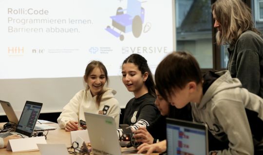 Eine Gruppe von Menschen, die mit Laptops um einen Tisch sitzen Eine Gruppe von Menschen, die mit Laptops um einen Tisch sitzen