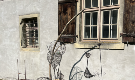 Ein Fenster mit Zaun und Drahtskulptur