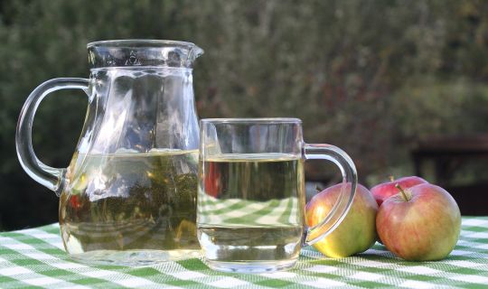Ein Glas FlÃ¼ssigkeit neben einem Krug Apfelsaft