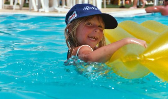 Ein Kind schwimmt in einem Pool mit einer Luftmatratze.