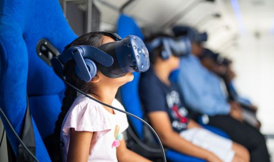 Ein Kind, das ein Virtual-Reality-Headset trägt und in einem Flugzeug sitzt Ein Kind, das ein Virtual-Reality-Headset trägt und in einem Flugzeug sitzt