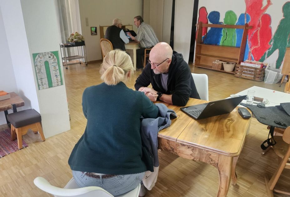 Eine Person und eine Person, die an einem Tisch mit einem Laptop sitzt