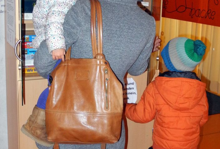 Eine Familie steht vor einem Schrank voller Brettspiele.