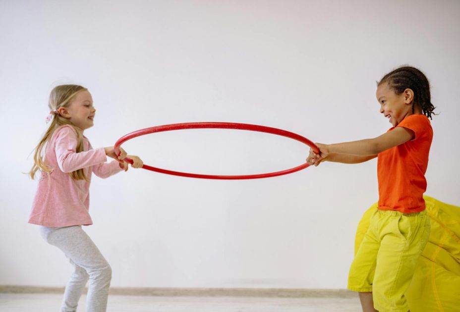 Eine Gruppe von Kindern, die mit einem Hula-Hoop-Reifen spielen. Eine Gruppe von Kindern, die mit einem Hula-Hoop-Reifen spielen.