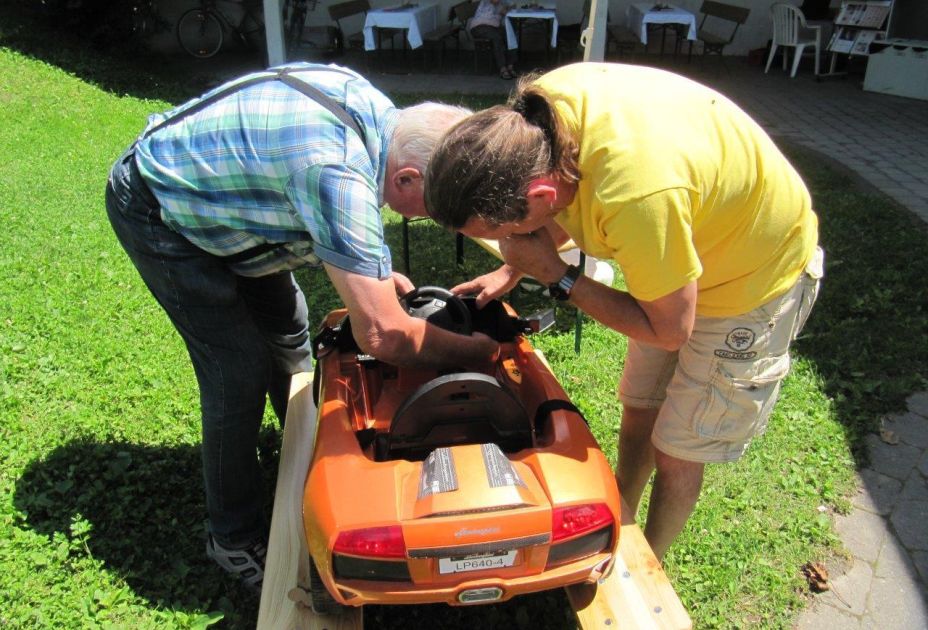 zwei Männer reparieren ein Spielzeugauto zwei Männer reparieren ein Spielzeugauto