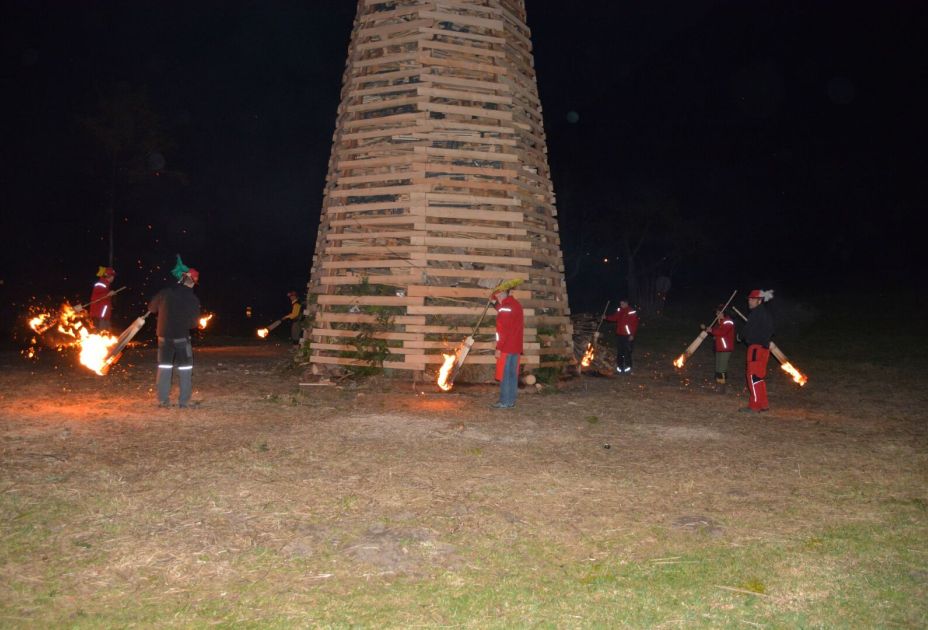 Eine Gruppe von Menschen, die Fackeln halten und vor einer Holzkonstruktion stehen Eine Gruppe von Menschen, die Fackeln halten und vor einer Holzkonstruktion stehen