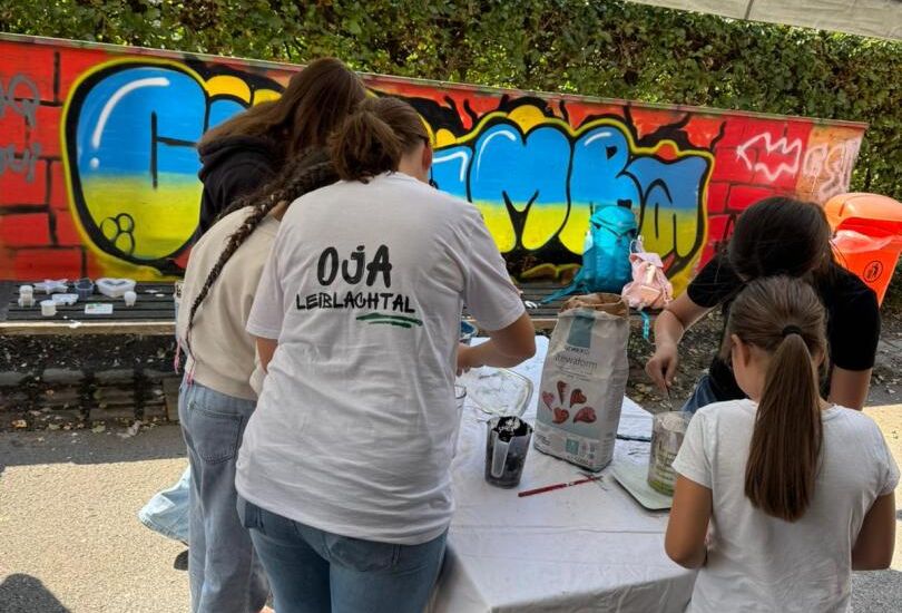 Eine Gruppe von Menschen, die um einen Tisch mit Graffiti bedeckten Tisch steht