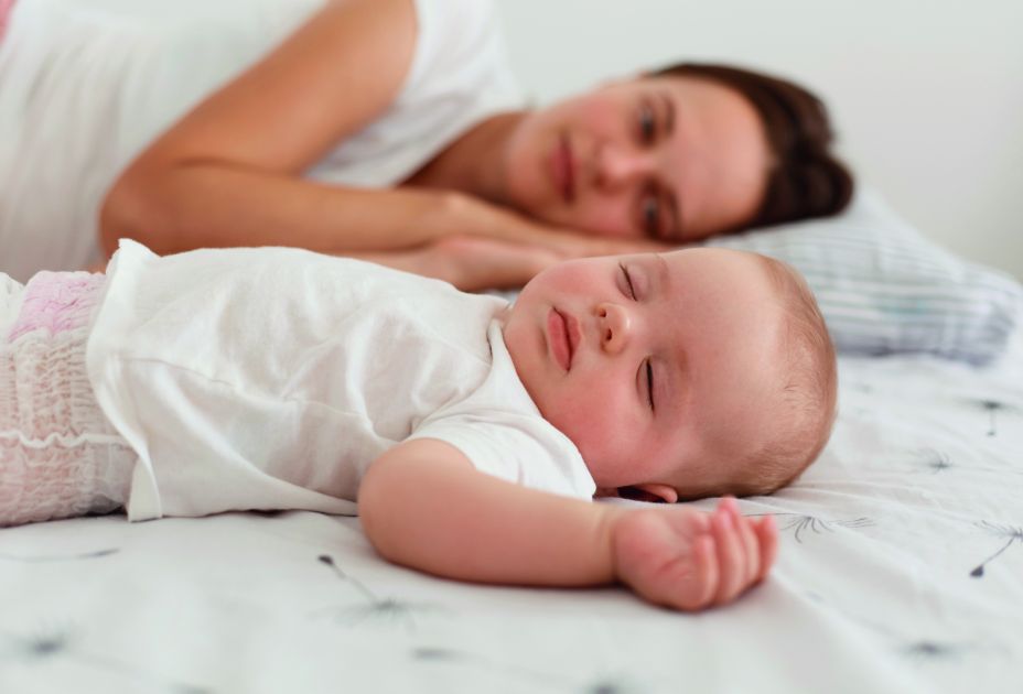 Eine Person und ein Baby, die auf einem Bett liegen