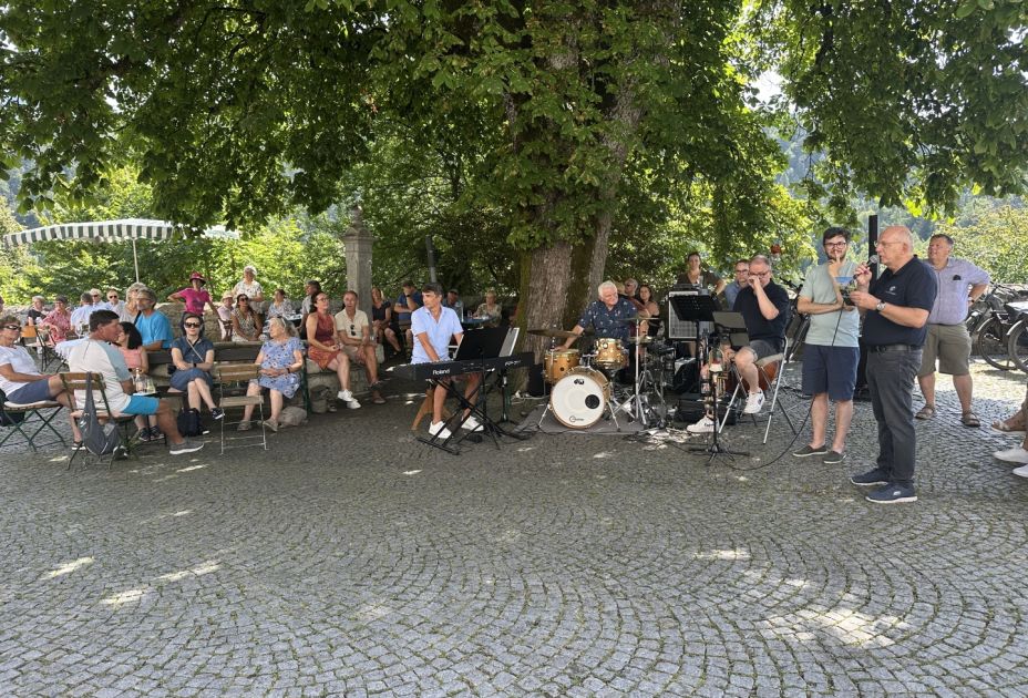 Eine Gruppe von Menschen, die auf BÃ¤nken saÃen, und eine Person, die Instrumente spielte