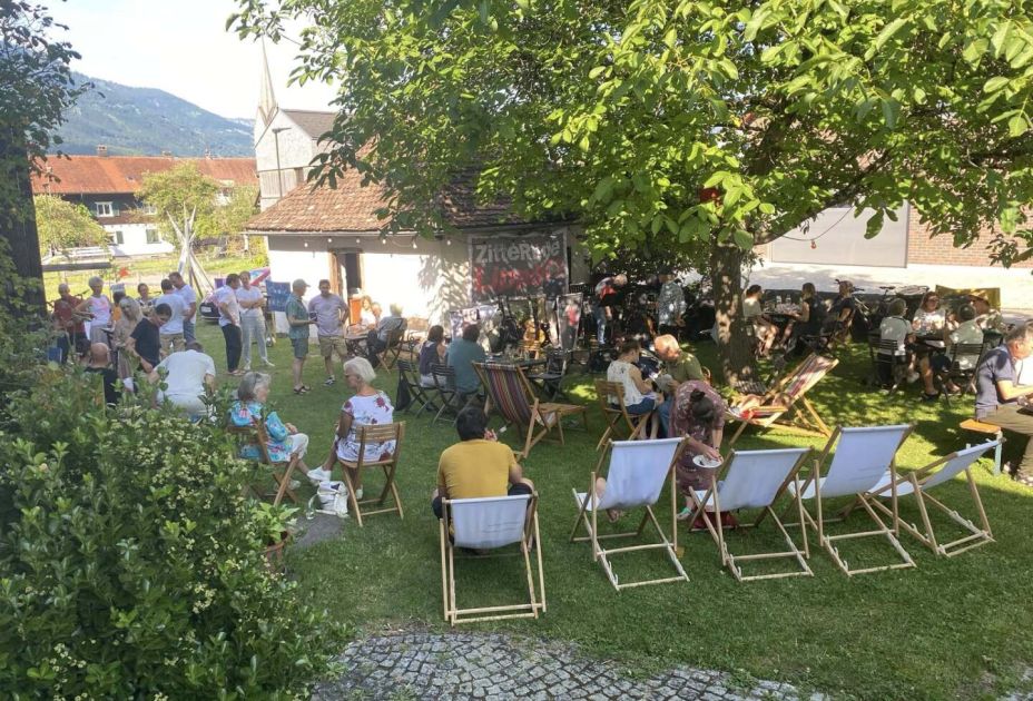 Eine Gruppe von Menschen, die drauÃen auf StÃ¼hlen sitzen